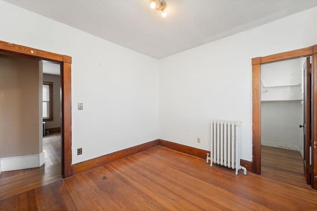 spare room with radiator heating unit and hardwood / wood-style flooring