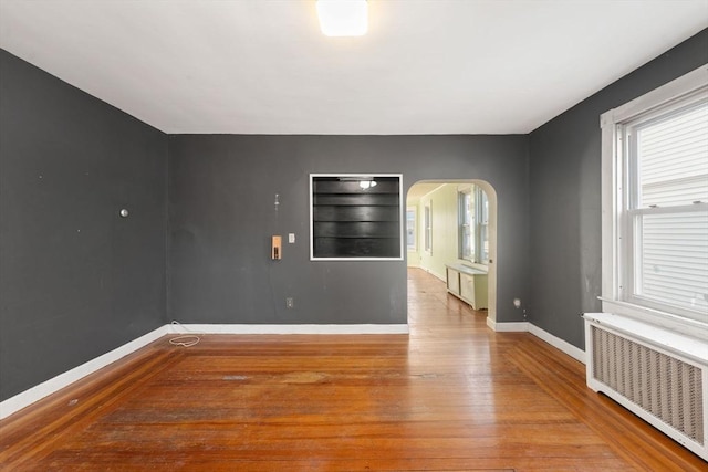 empty room featuring radiator heating unit and hardwood / wood-style floors