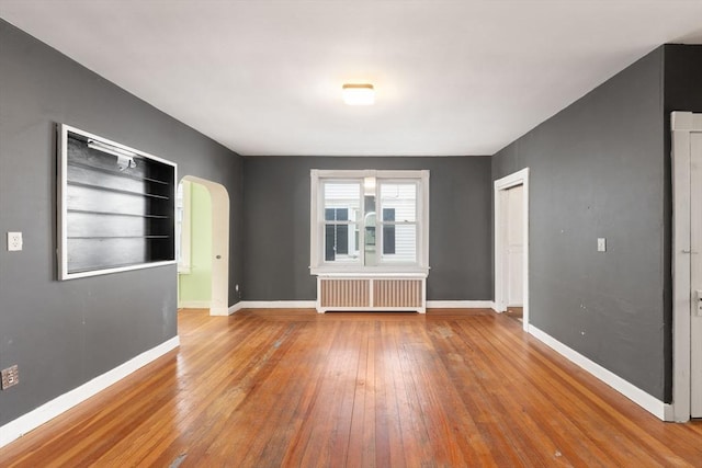 spare room featuring radiator heating unit and light hardwood / wood-style floors