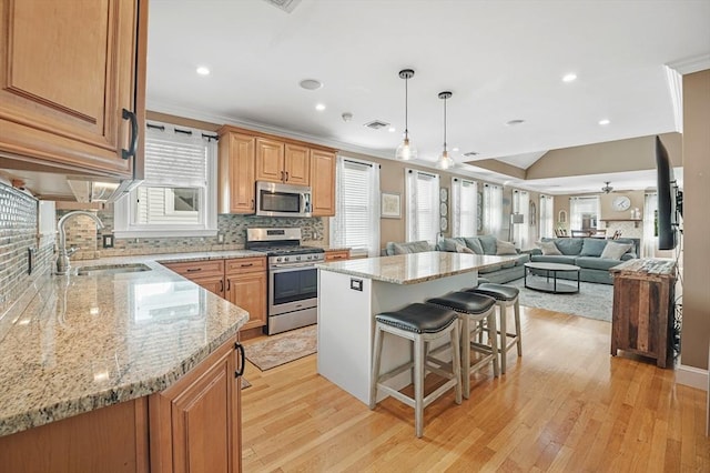 kitchen with a breakfast bar, sink, a center island, stainless steel appliances, and light hardwood / wood-style flooring