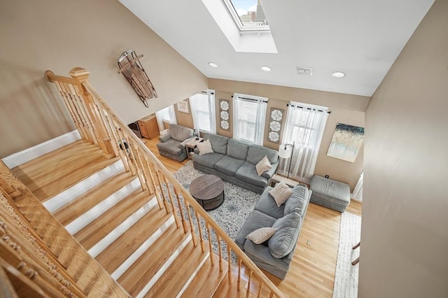 living room featuring hardwood / wood-style flooring and vaulted ceiling with skylight