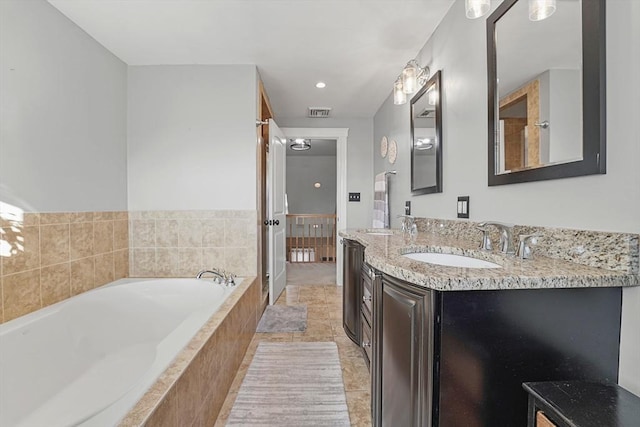 bathroom with a relaxing tiled tub, tile patterned floors, and vanity