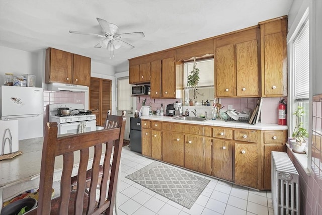 kitchen with tasteful backsplash, white appliances, radiator, and sink