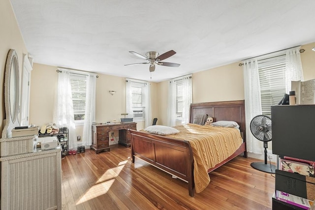 bedroom featuring cooling unit, hardwood / wood-style floors, and ceiling fan