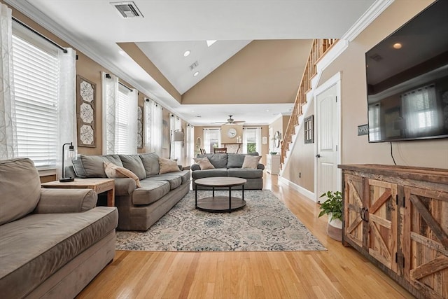 living room with ornamental molding, a healthy amount of sunlight, vaulted ceiling, and light wood-type flooring