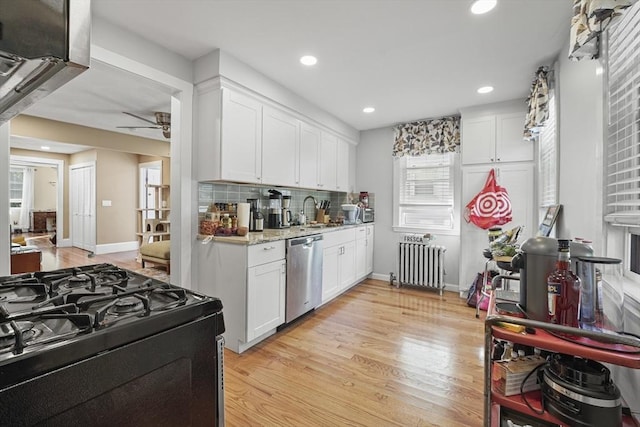 kitchen featuring stainless steel dishwasher, radiator heating unit, range with gas stovetop, and white cabinets