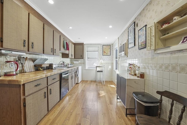 kitchen featuring sink, ornamental molding, stainless steel dishwasher, tile counters, and light wood-type flooring