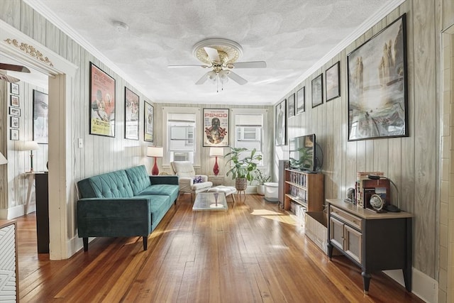 living area with crown molding, ceiling fan, dark wood-type flooring, and a textured ceiling