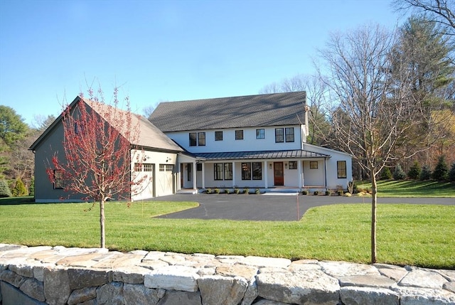 view of front of house featuring covered porch, a front yard, and a garage