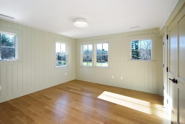 unfurnished room featuring wooden walls and light hardwood / wood-style floors