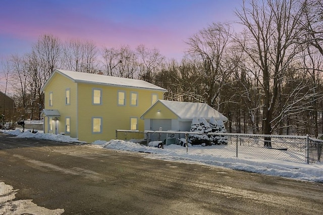 snow covered back of property with a garage