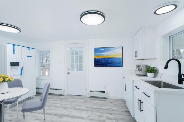 kitchen featuring dishwasher, white cabinetry, a baseboard heating unit, sink, and light hardwood / wood-style flooring