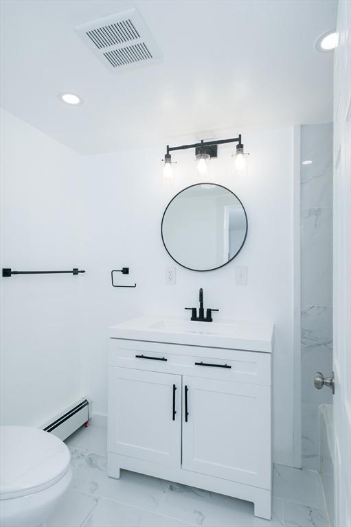 bathroom featuring a baseboard heating unit, vanity, and toilet