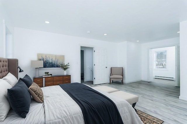 bedroom with light wood-type flooring and a baseboard heating unit