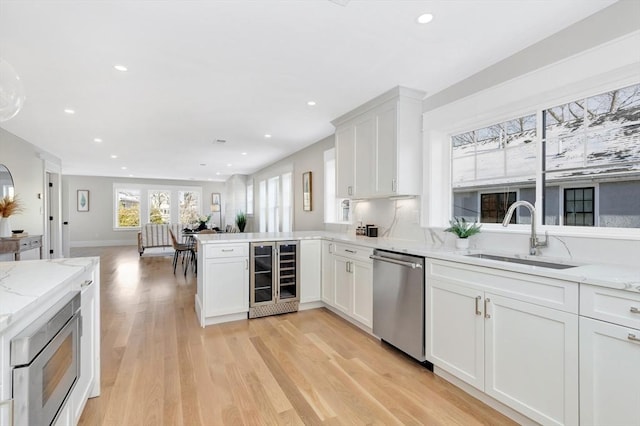 kitchen featuring sink, kitchen peninsula, wine cooler, white cabinetry, and stainless steel appliances