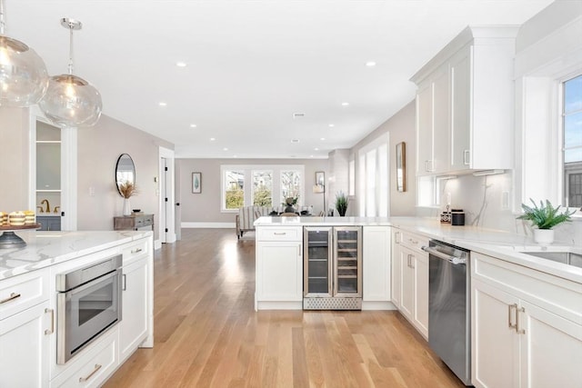 kitchen featuring pendant lighting, dishwasher, white cabinets, wine cooler, and light hardwood / wood-style floors