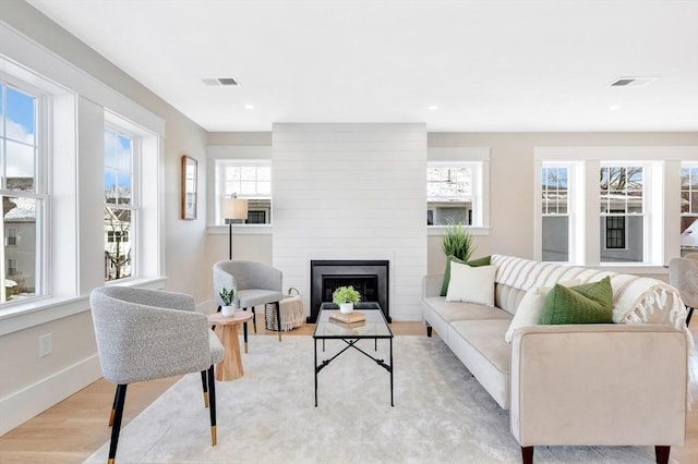 living room with a wealth of natural light, a fireplace, and light wood-type flooring