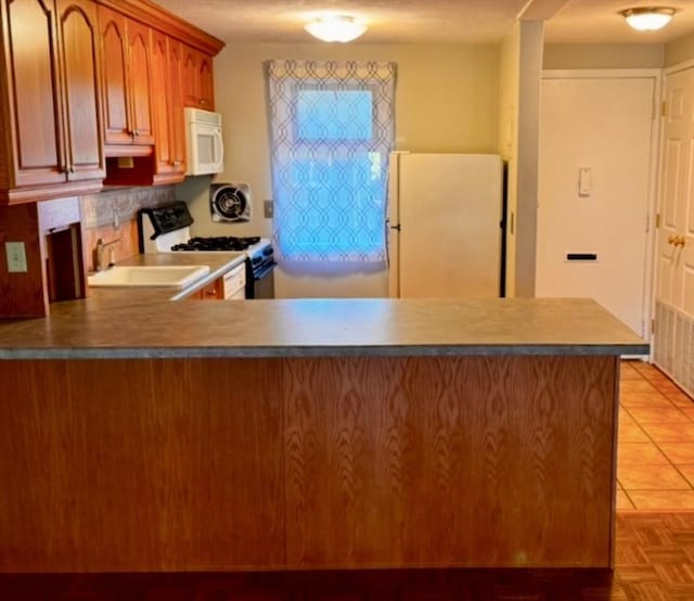 kitchen with kitchen peninsula, light tile patterned floors, white appliances, and sink