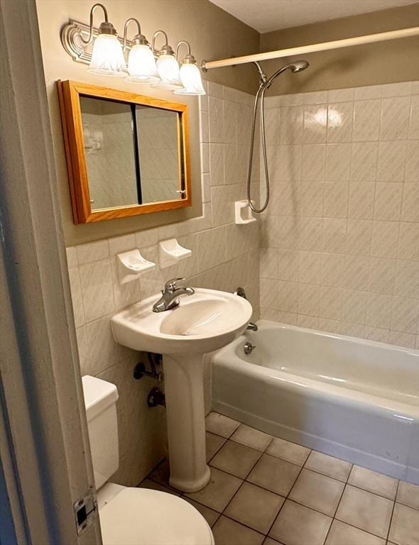 bathroom with tile patterned floors, tiled shower / bath combo, tile walls, and toilet