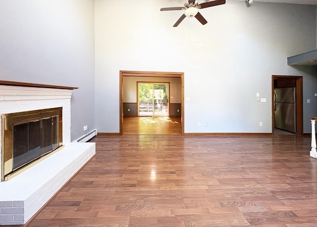 2 Robert Cohen Dr, Canton, MA 02021 - unfurnished living room with baseboard heating, a high ceiling, a ceiling fan, a fireplace, and wood finished floors