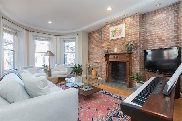 living room featuring ornamental molding, wood-type flooring, a fireplace, and brick wall