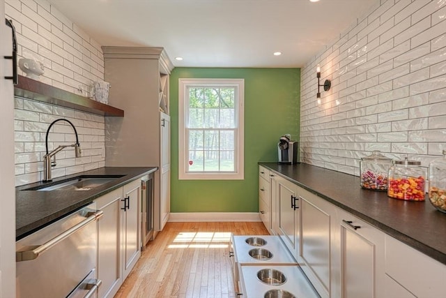 kitchen with open shelves, a sink, dishwasher, dark countertops, and backsplash