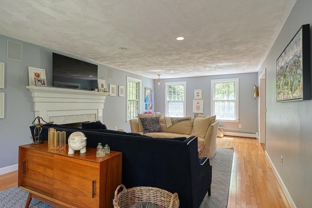 living area with a baseboard radiator, light wood-type flooring, baseboards, recessed lighting, and a fireplace