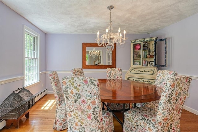 dining room with a chandelier, a textured ceiling, wood finished floors, plenty of natural light, and baseboard heating