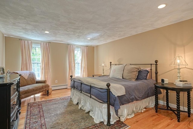 bedroom featuring a baseboard heating unit, light wood finished floors, recessed lighting, and baseboards