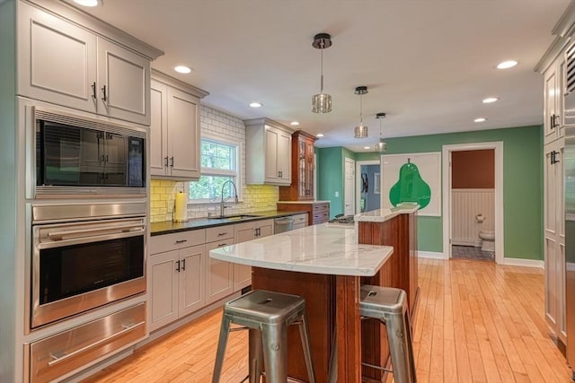kitchen featuring stainless steel appliances, a warming drawer, a kitchen island, a sink, and recessed lighting
