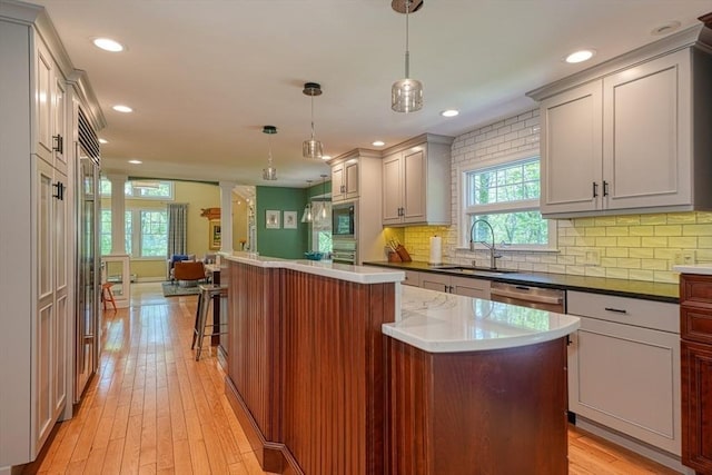 kitchen with a sink, a center island, light wood-style flooring, decorative backsplash, and recessed lighting
