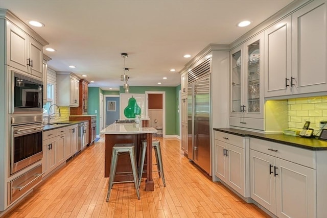 kitchen with built in appliances, a kitchen island, recessed lighting, dark countertops, and tasteful backsplash