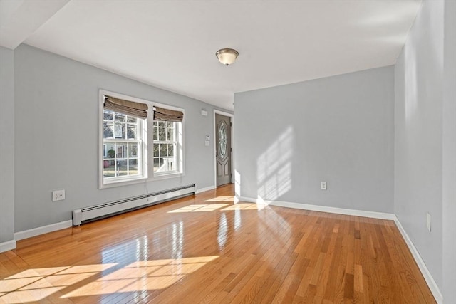 spare room featuring baseboards, light wood finished floors, and a baseboard radiator