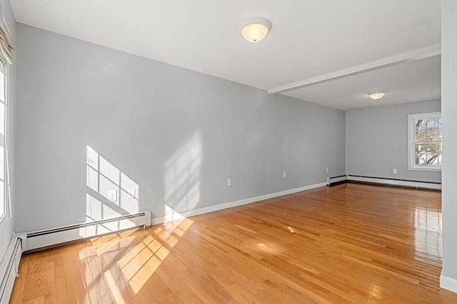 spare room with baseboard heating, hardwood / wood-style floors, baseboards, and a baseboard radiator