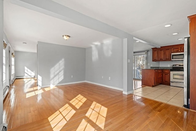 unfurnished living room featuring a baseboard heating unit, baseboards, baseboard heating, recessed lighting, and light wood-style floors