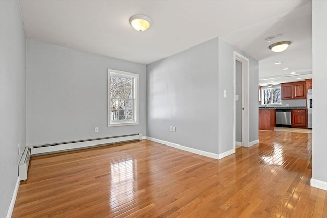 spare room with baseboards, light wood-type flooring, and baseboard heating