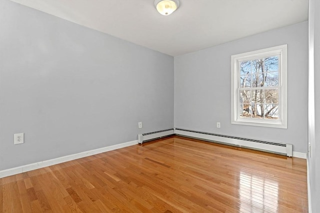 spare room with a baseboard heating unit, wood finished floors, and baseboards