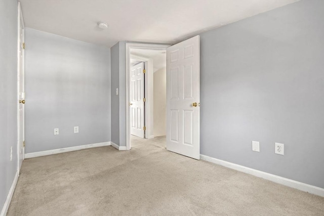 empty room featuring light carpet and baseboards