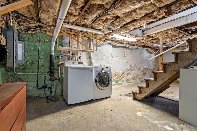 unfinished below grade area featuring electric panel, stairway, and washing machine and dryer