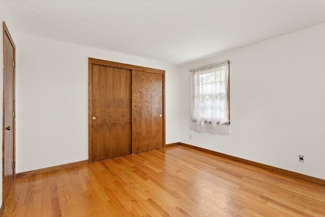 82 Neponset St Unit E, Canton, MA 02021 - unfurnished bedroom with light wood finished floors, baseboards, and a closet