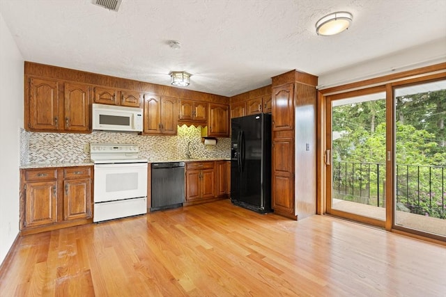 82 Neponset St Unit E, Canton, MA 02021 - kitchen with black appliances, brown cabinets, light wood-style flooring, tasteful backsplash, and a textured ceiling