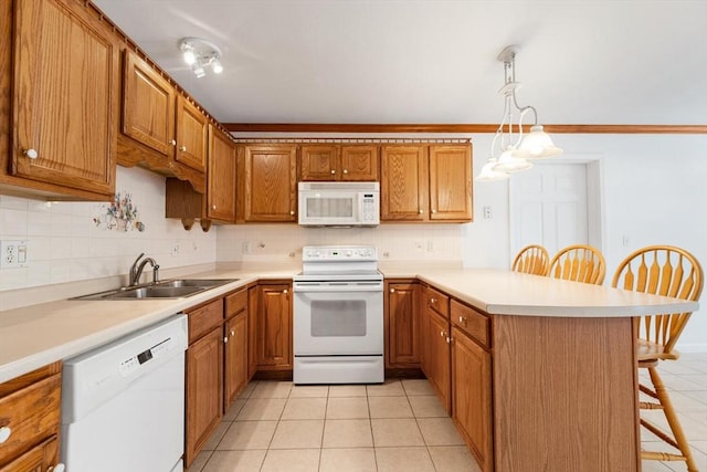 kitchen featuring white appliances, a peninsula, a breakfast bar, a sink, and decorative backsplash