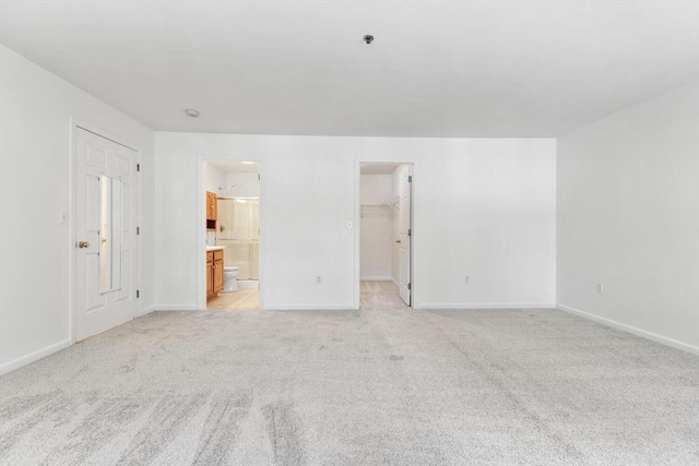 spare room with baseboards and light carpet