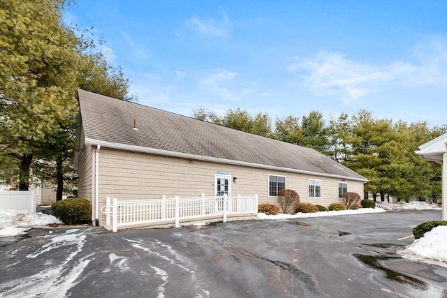 view of side of home featuring roof with shingles and fence