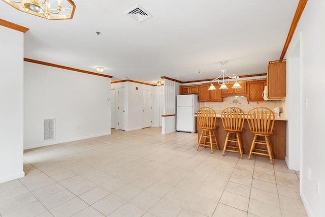 kitchen featuring freestanding refrigerator, a notable chandelier, ornamental molding, and visible vents