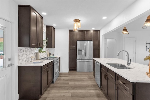 kitchen featuring pendant lighting, sink, dark brown cabinets, stainless steel appliances, and light wood-type flooring