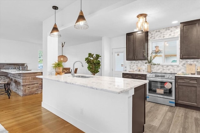 kitchen featuring dark brown cabinetry, sink, stainless steel electric range, light wood-type flooring, and light stone countertops