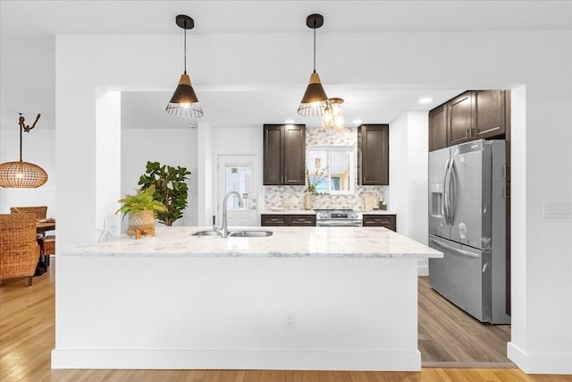 kitchen featuring kitchen peninsula, sink, light hardwood / wood-style floors, light stone counters, and stainless steel appliances