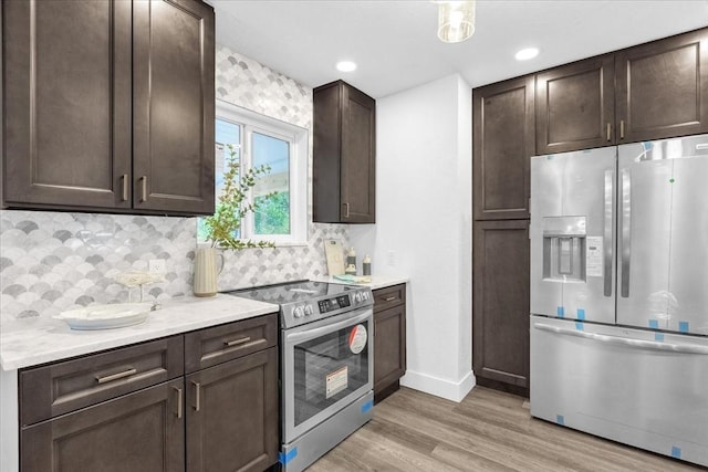 kitchen featuring dark brown cabinetry, decorative backsplash, stainless steel appliances, and light wood-type flooring