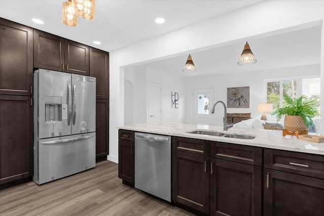 kitchen with sink, dark brown cabinets, appliances with stainless steel finishes, a healthy amount of sunlight, and light hardwood / wood-style floors